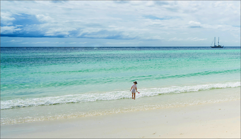 Beach image, with the little girl now appearing larger and moved so it looks like she is standing in the waves.